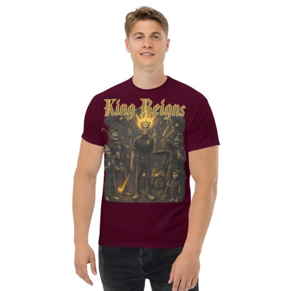 Maroon t-shirt with “King Reigns” graphic featuring a crowned king golfing beside a golf cart, bold golden lettering.